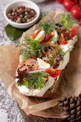 Open rustic sandwiches with vegetables, tomato, boiled egg. Homemade sandwich with ham, cucumber, radish sprouts on wooden board, top view