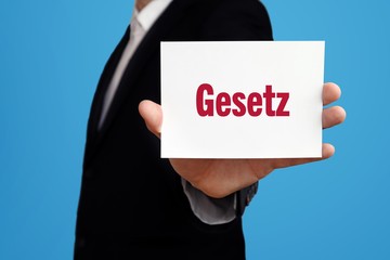 Gesetz. Geschäftsmann im Anzug zeigt Karte mit Text. Mann isoliert vor Hintergrund (blau)