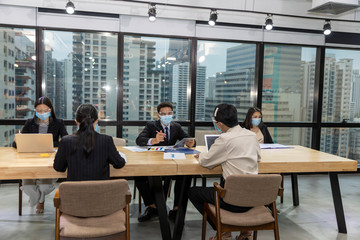 Fototapeta na wymiar Business in new normal. Office workers wearing face mask and protection while having internal meeting for new business strategy or plan. Technology for new normal
