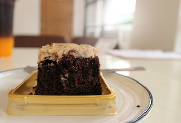 Chocolate brownie with a spoon on a plate in a coffee shop.