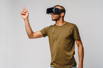 Naklejka premium Young African American man wearing vr virtual reality headset over grey background