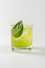 Alcoholic cocktail with basil in glass goblet on white background