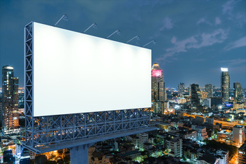 Blank white road billboard with Bangkok cityscape background at night time. Street advertising poster, mock up, 3D rendering. Side view. The concept of marketing communication to sell idea.