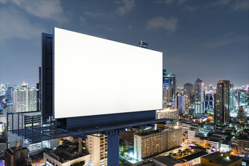 Blank white road billboard with Bangkok cityscape background at night time. Street advertising poster, mock up, 3D rendering. Side view. The concept of marketing communication to sell idea.