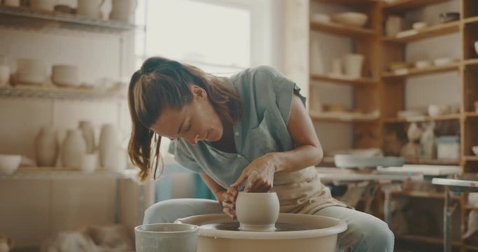 Young artist in the pottery studio making bowl with her hands, handmade creative artist