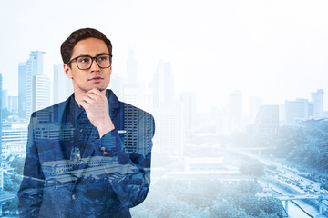 Young handsome businessman in suit and glasses dreaming about new career opportunities after MBA graduation. Kuala Lumpur on background. Double exposure.