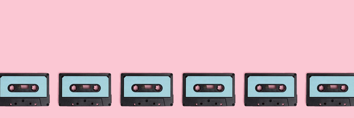 Row of cassette tapes on a pink pastel background. Creative banner with place for text.