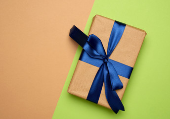 rectangular box wrapped in brown paper and tied with a silk ribbon with a bow