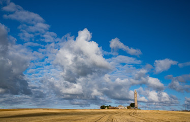 Rattoo round tower in rural county kerry, passing clouds and blue sky background