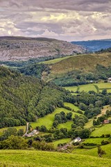 Fototapeta na wymiar View from Horseshoe Pass, Llantysilio, North Wales showing farmland pastures, forest, moorlands and stone escarpment. 