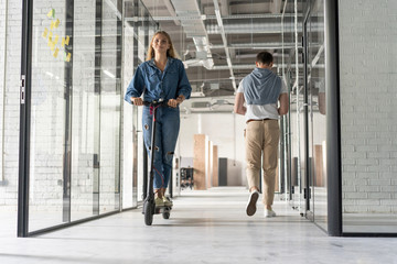 beautiful young woman riding scooter at modern open space office © opolja