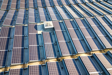 Aerial view of many photo voltaic solar panels mounted of industrial building roof.