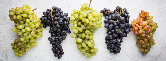 different colors, red, pink and white grapes over stone table. Top view with copy space