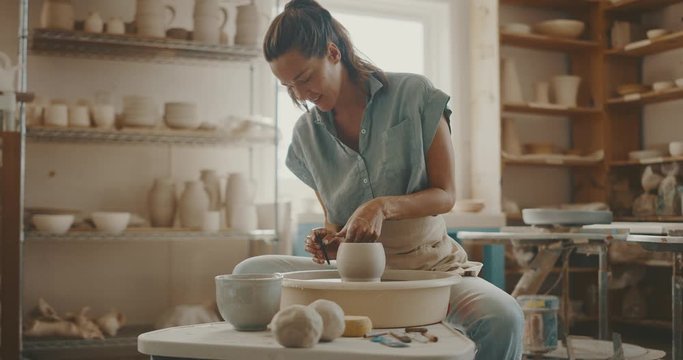 Young artist in the pottery studio making bowl with her hands, handmade creative artist