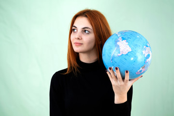 Portrait of a happy young woman holding geographic globe of the world in her hands. Travel destination and planet protection concept.