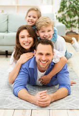 Positive Family Of Four Lying Posing On Floor Indoors