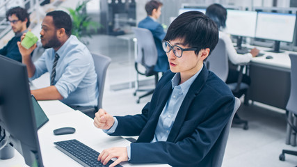 Young Professional Japanese Stock Broker Celebrates a Successful Deal. Diverse and Motivated Business People Work on Computers in Modern Open Office.