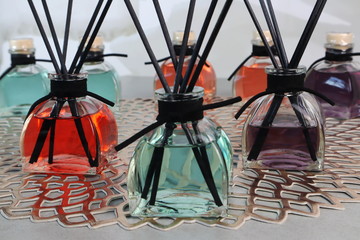 luxury glass aroma reed diffuser bottle with blue , green and pink colour oil are displayed on the white table in the white living room