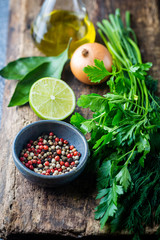 Fragrant fresh parsley and dill with pepper peas, onion and lime arranged on a dark wooden background.