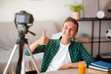 Cheerful teenager showing thumb up, broadcasting from home