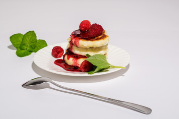 Delicious and healthy cottage cheese pancakes on a white saucer, poured with BlackBerry jam.