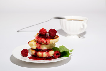Delicious and healthy cottage cheese pancakes on a white saucer, poured with BlackBerry jam.