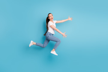 Fototapeta na wymiar Full length profile side photo of energetic girl greet her friend jump run hug open hands wear white t-shirt gumshoes isolated over blue color background