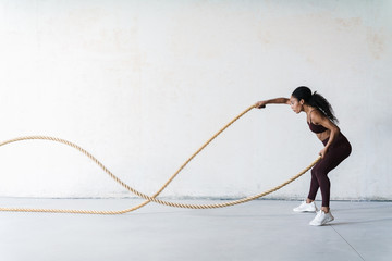 Portrait of young african american woman doing workout with battle rope