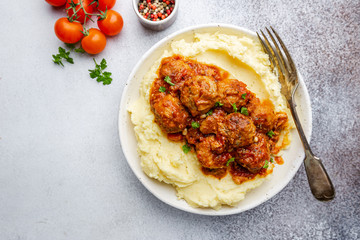 Meatballs in tomato sauce with mashed potato on the white plate, top view, view from above