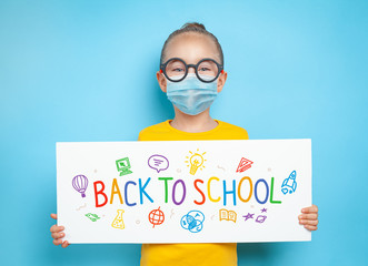 Beautiful cute little girl with glasses wearing protective medical mask and holding a white paper with message