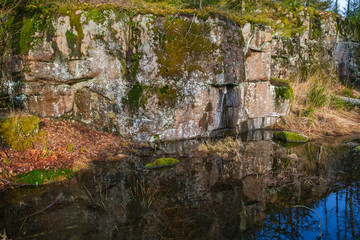 Rock cliff by a pond with reflections in the water