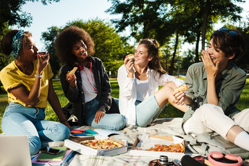 Image of funny nice student girls eating pizza while doing homework