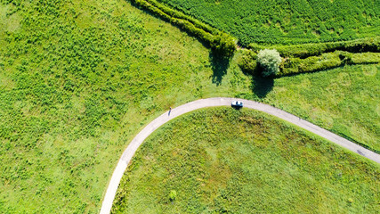 Vista aerea dal drone di una strada di campagna in mezzo a campi e prati con ombre di alberi