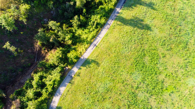 Vista aerea dal drone di una strada di campagna in mezzo a campi e prati con ombre di alberi