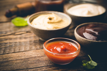 Classic set of sauces, American yellow mustard, ketchup, barbecue sauce, mayonnaise on wooden...