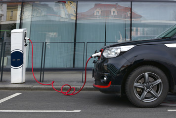 Modern electric car plugged in charging on the street station. New energy vehicles, environment friendly alternative energy for cars