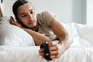 Exhausted man being awakened by an alarm clock