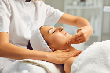 Obraz na płótnie Canvas Facial massage or treatment for young womans face in beauty spa salon, side view
