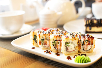 Delicious hot rolls with salmon, cream cheese Philadelphia, cucumber and eel on white plate. Selective focus.