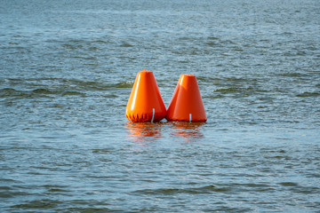 Two inflatable orange buoys in a lake