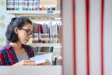 Female college student read book between bookshelf