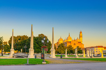 Obraz premium Padua cityscape with statues near bridge across small canal on Piazza Prato della Valle square in historical city centre, Abbey of Santa Giustina church, Padova town, Veneto Region, Italy