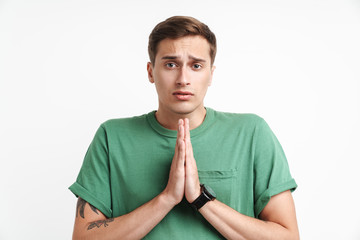 Image of uptight caucasian man praying and holding palms together