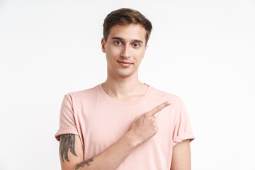 Image of brunette young man in t-shirt smiling and pointing finger aside