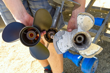 man changing propeller on outboard motor. Repairing outboard motor for boat, replacing screw.