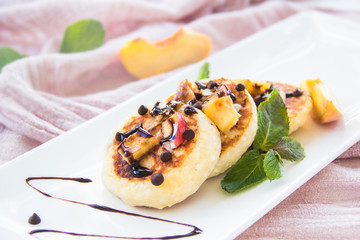A healthy breakfast of pancakes, peach, chocolate, and honey