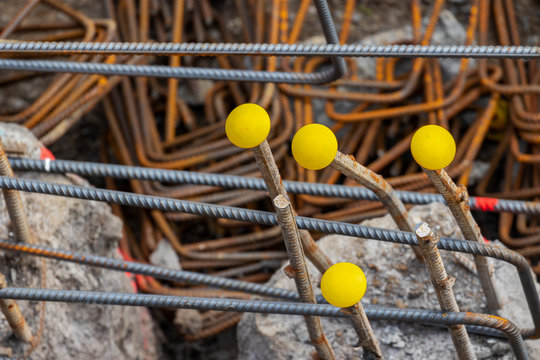 Steel reinforcement rebars with yellow protection caps. Covers protect workers from impalement on hazardous protruding metal thread bars rods used during construction pile process in building sites. 