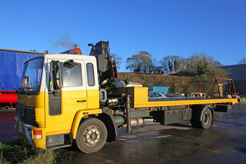Fototapeta na wymiar Yellow recovery truck with crane