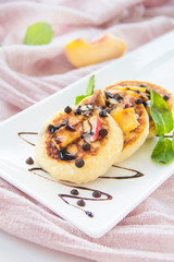 A healthy breakfast of pancakes, peach, chocolate, and honey