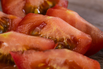 Saftige rote Tomatenstücke liegen auf einem hölzernen Brettchen, frische Zubereitung